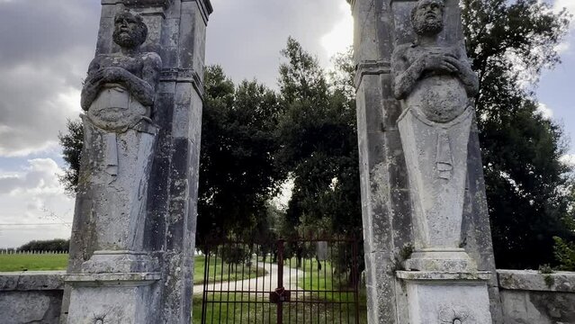 Mammalocchi busts travertine columns with allegorical figures standing at entrance to private villa in Umbria, Italy. Tilt down
