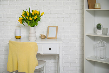 Beautiful vase of yellow tulips on dressing table in bedroom