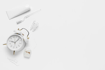 Alarm clock, toothpaste, dental floss and toothbrush isolated on white background