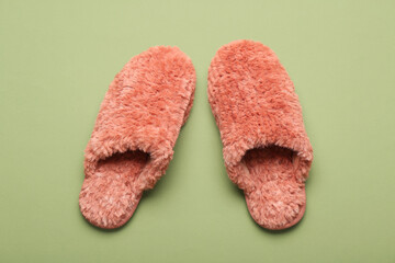 Pair of soft red slippers on green background. Top view