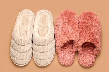 Two pairs of soft slippers on beige background. Top view