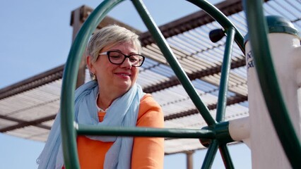 Closeup of mature woman using public adapted fitness machine. Exercising on elderly age concept.