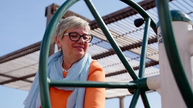 Closeup of mature woman using public adapted fitness machine. Exercising on elderly age concept.