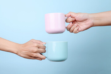 Female hands holding blue and pink cup hot coffee mockup isolated on blue background