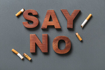 Text SAY NO and cigarettes butts on grey background. Stop smoking concept.