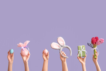 Female hands with gift egg, gift, painted eggs, bouquet of hyacinths and bunny ears headband on...