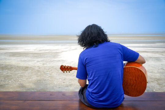 child playing guitar on the beach with dramatic tone