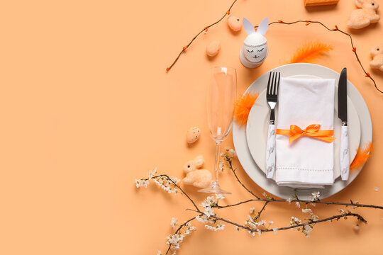 Plates with napkin, cutlery and Easter eggs on orange background