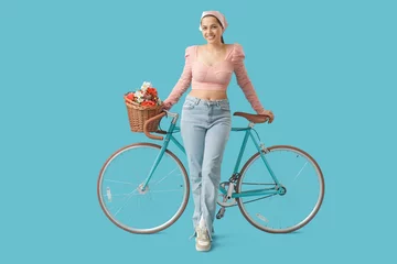 Küchenrückwand glas motiv Beautiful young woman with bicycle and bouquet of flowers on blue background © Pixel-Shot
