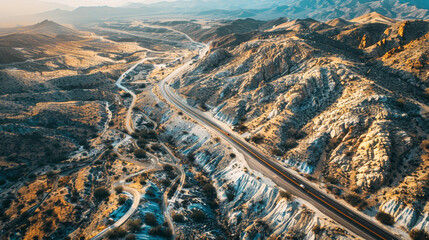 Aerial view of a highway passing through mountains, canyons and arid landscapes