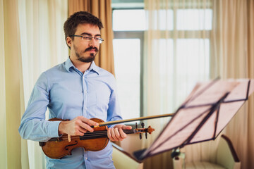 Man playing violin at home. He is practicing for live performance.