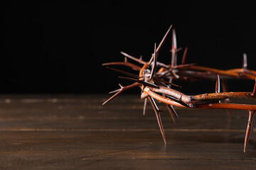 Crown of thorns on wooden table against black background, closeup. Good Friday concept