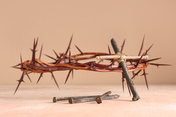 Crown of thorns with cross and nails on beige background, closeup. Good Friday concept
