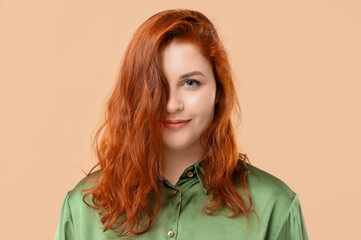 Beautiful young redhead woman in green blouse on beige background