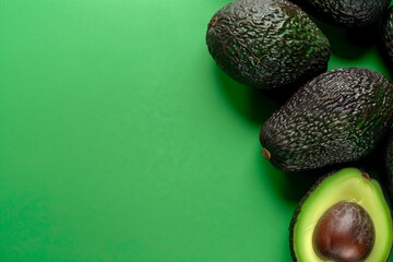 Fresh organic hass avocados on a green background, top view with copy space