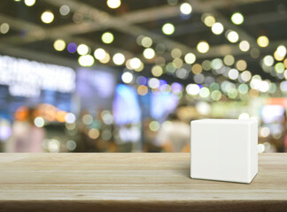 White block cube on wooden table over blur light and shadow of shopping mall