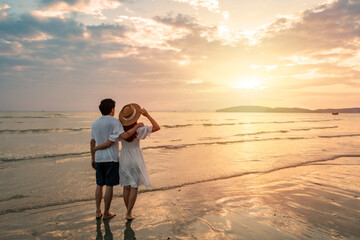 Young couple traveler looking beautiful sunset on the beach, Couple on vacation in summer concept - 772826037