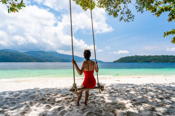 Young woman traveler enjoying on the swing at beautiful tropical white sand beach, Summer vacation and Travel concept - 772826046