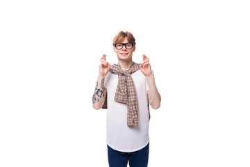 stylish red-haired guy in glasses and a plaid shirt crossed his fingers on a studio background