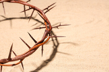 Crown of thorns on sand background, closeup. Good Friday concept
