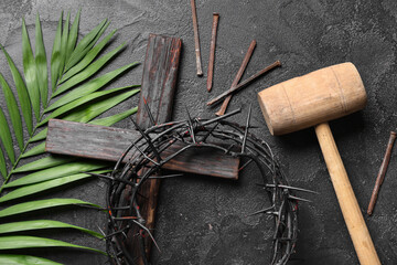 Crown of thorns with palm leaf, wooden hammer and nails on black grunge background. Good Friday...