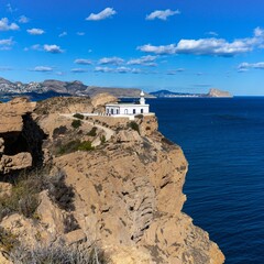 view of the Albir Lighthouse on the rocky promontory in the Serra Gelada Natural Park between...
