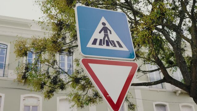 Closeup on road sign of pedestrian crossing on city street on building background. Warning symbol for drivers. 