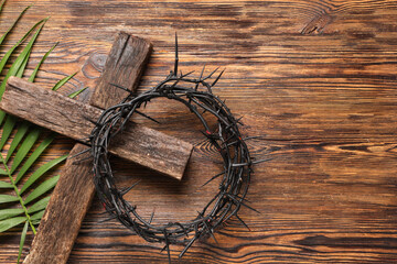 Crown of thorns with cross and palm leaf on wooden background. Good Friday concept