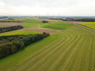 Aerial view of a farmland with fields, trees, a road and electricity generators 