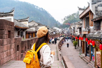 Young female tourist looking at the beautiful landscape of Feng Huang Ancient Town, The famous tourist destination at Hunan Province, China - 772831693