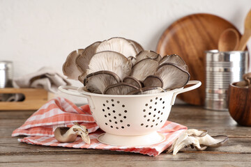 Colander with fresh oyster mushrooms on wooden table