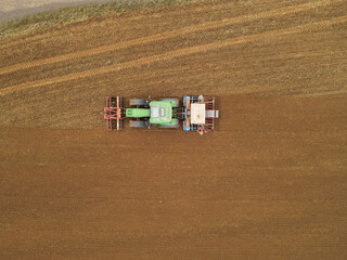 View from above of a tractor plowing and sowing the farmland