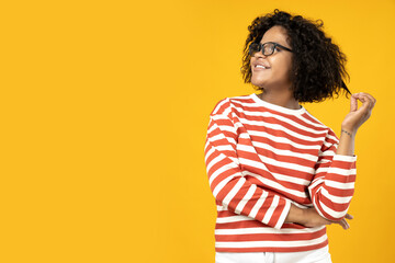 A young African American woman in glasses poses on a yellow background