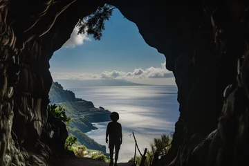 Deurstickers person silhouetted against ocean view from cave entrance © Natalia