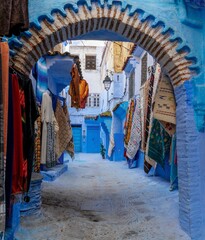 arched doorway with colourful carpets on the wall in the historic blue city of Chefchaouen in northern Morocco