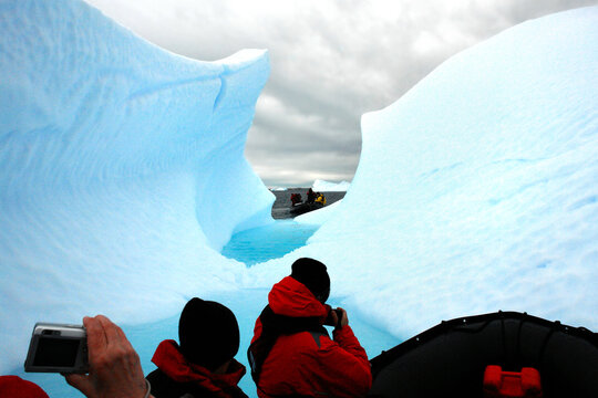 Tourists in Antarctica on a pontoon admiring an iceberg