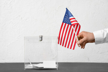 Voting man with flag of USA near ballot box on table against white background