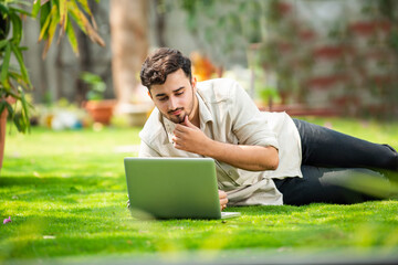 Indian man sitting on glass and using computer