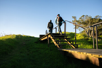 Couple walking up stairs on the boardwalk around the crater at Mt Eden summit. Auckland.