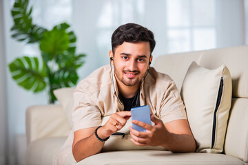 indian man using smartphone on sofa