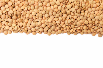 Uncooked brown lentils border on white background. Copy space for text. Top view