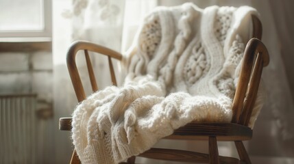 A cozy white knitted sweater on a wooden chair. - 772844884