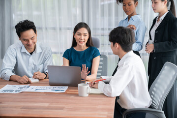 Multiracial analyst team use BI dashboard data to analyze financial report on meeting table. Group of diverse business people utilize data analysis by FIntech for success business marketing. Concord