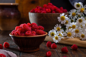Fresh raspberries in a clay and wooden bowl on a dark wooden table