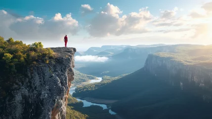  Person standing on a high cliff edge with a breathtaking view of a river and mountains during sunset. © Artsaba Family