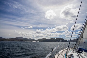 Fototapeta premium exploring the oceans and world while sailing a yacht with a sail on a beautiful day exploring the australian coastline of tasmania