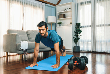 Athletic and sporty man doing pushup on fitness mat during home body workout exercise session for...