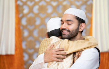 Happy indian Muslim father with kid hugging each other while saying ramadan feast wishes at home -...