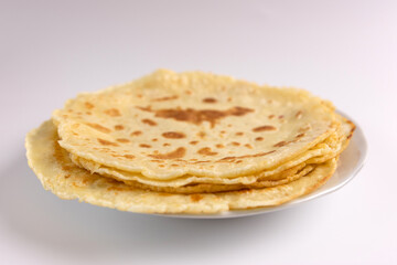 Freshly baked pancakes on a plate on a white background.