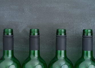 Four open wine bottles standing in a row against black background. Close-up